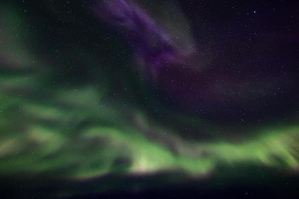 Ein Blick fast senkrecht nach oben in den Nachthimmel über Island, während Polarlichter im Himmel wabern.

Insgesamt ist der Himmel fast schwarz und von vielen hellen kleinen Punkten, den Sternen, bevölkert.

In der oberen Mitte des Bildes sieht man blaue und violette Lichter, die wie in einem Kranz auseinander driften. Eine Corona.

Links und in der gesamten unteren Hälfte des Bildes erstreckt sich ein Band mit grünen Lichtern, wobei an deren oberen Ende ein Hauch von roten Lichtern erkennbar ist.